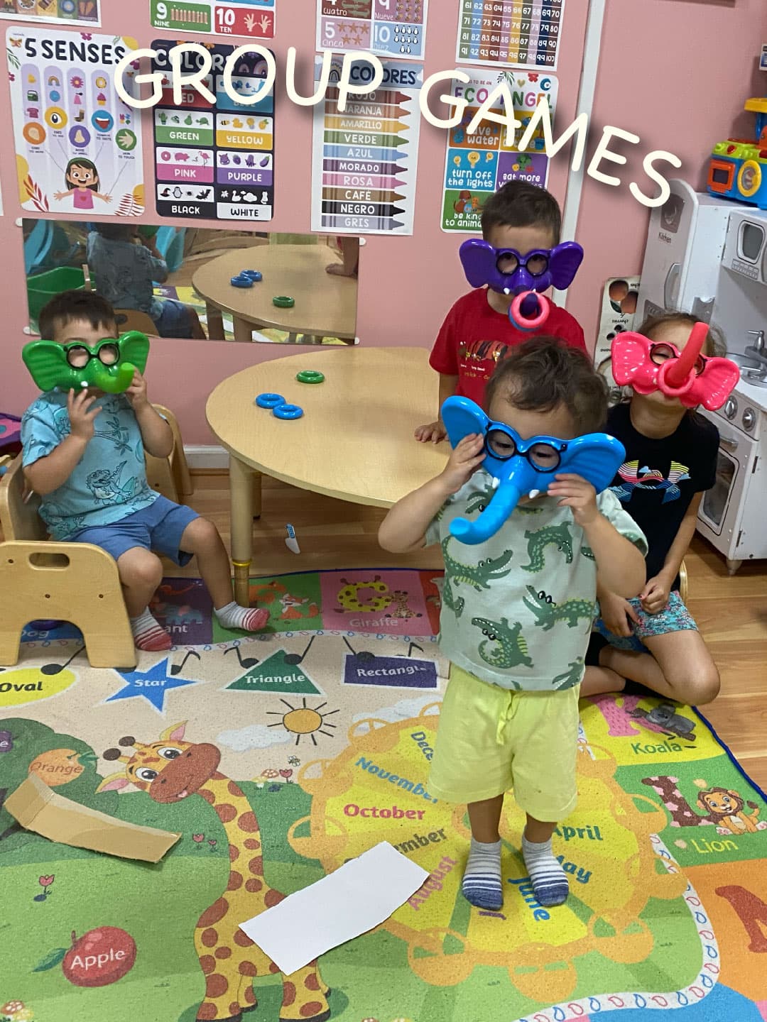 Children holding up elephant masks in green, purple, blue and pink during a group game in the playroom.