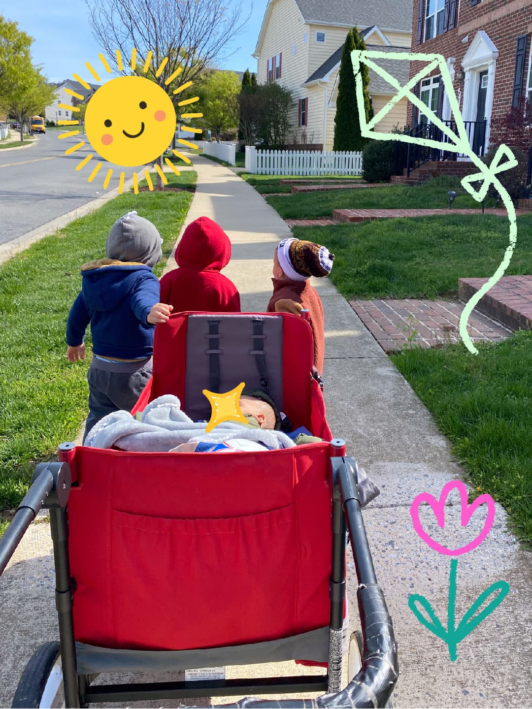Three toddlers walking beside a red stroller with a baby in it, on the way to the park along a Clarksburg Village sidewalk.