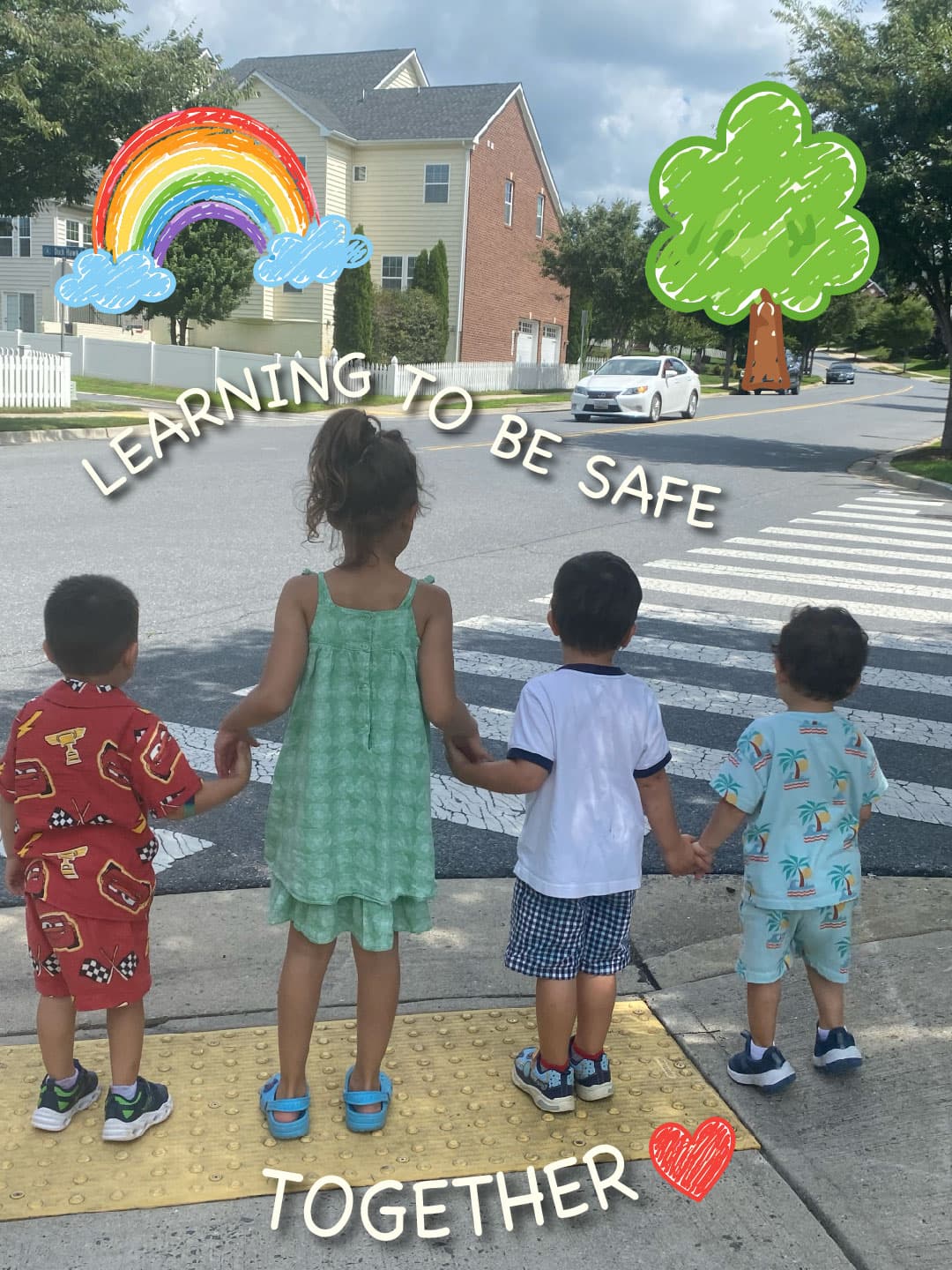 Four children holding hands at the kerb, learning to cross the road safely on a walk through Clarksburg Village, Maryland.
